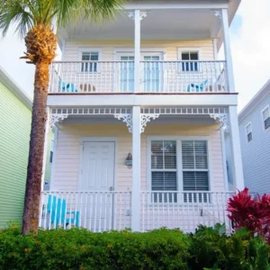 Two-story pastel coastal house with palm tree