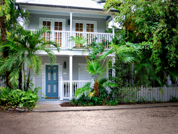 Two-story cottage with blue door and palms